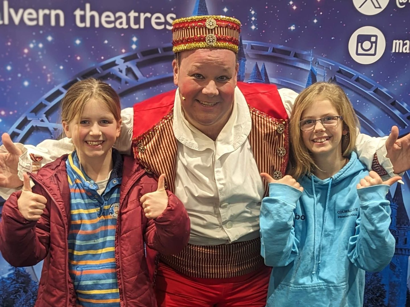 Libby and Lia stand with Mark James, the star of Cinderella pantomime at Malvern Theatres