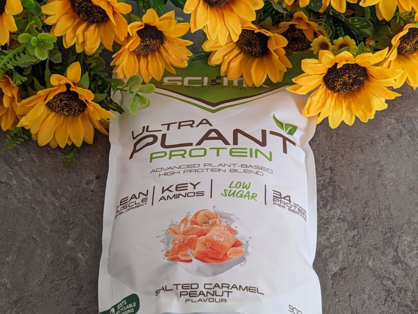 Packet of salted caramel flavour vegan protein shake displayed against a bunch of sunflowers.