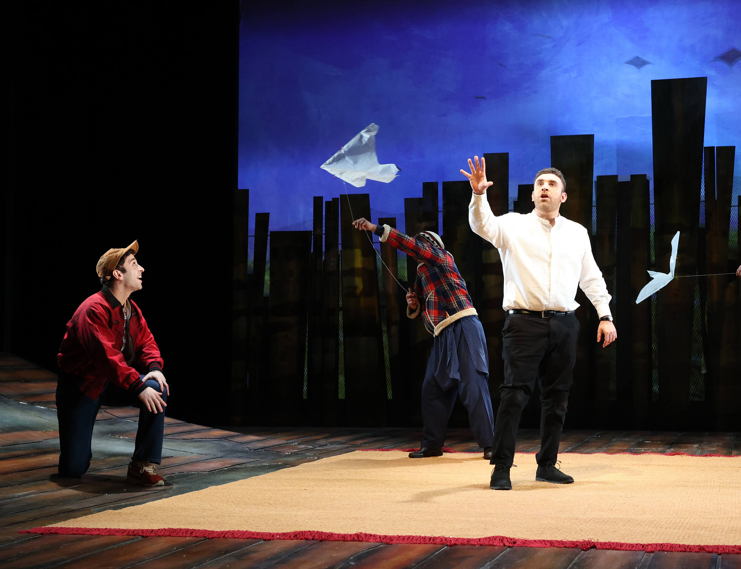 Three cast members from the Kite runner on stage at Malvern Theatres with kites