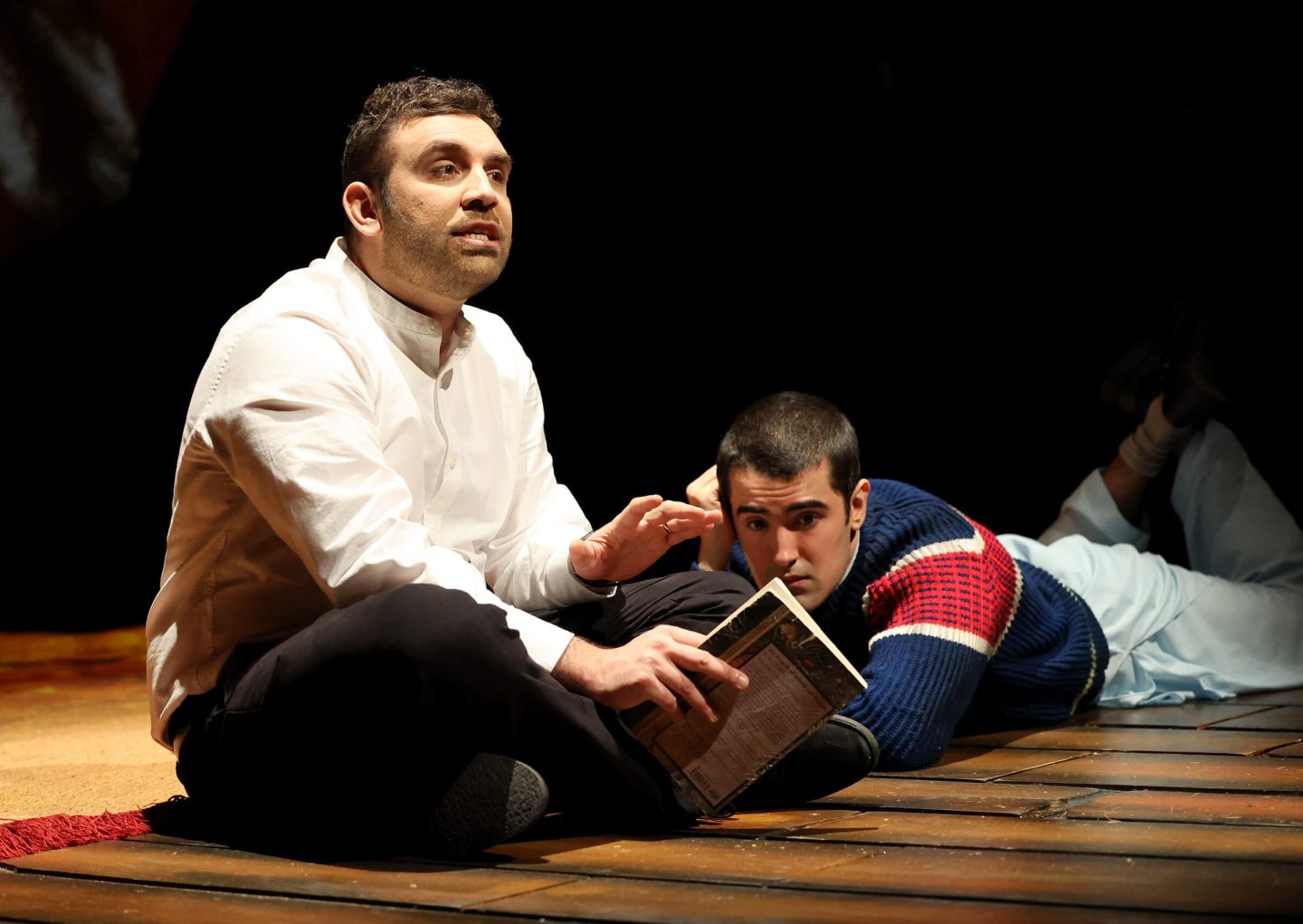 Two cast members from the Kite runner on stage at Malvern Theatres with one holding a book and the other reaching for it