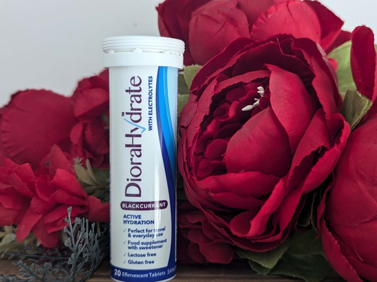 DioraHydrate pack displayed in front of a bunch of red Christmas flowers