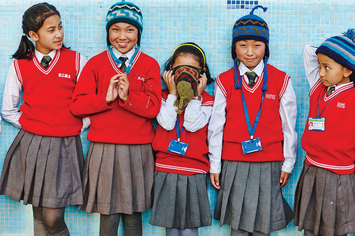 Children at a school in Nepal wearing grey skirts and red jumpers with school uniform skirt and tie