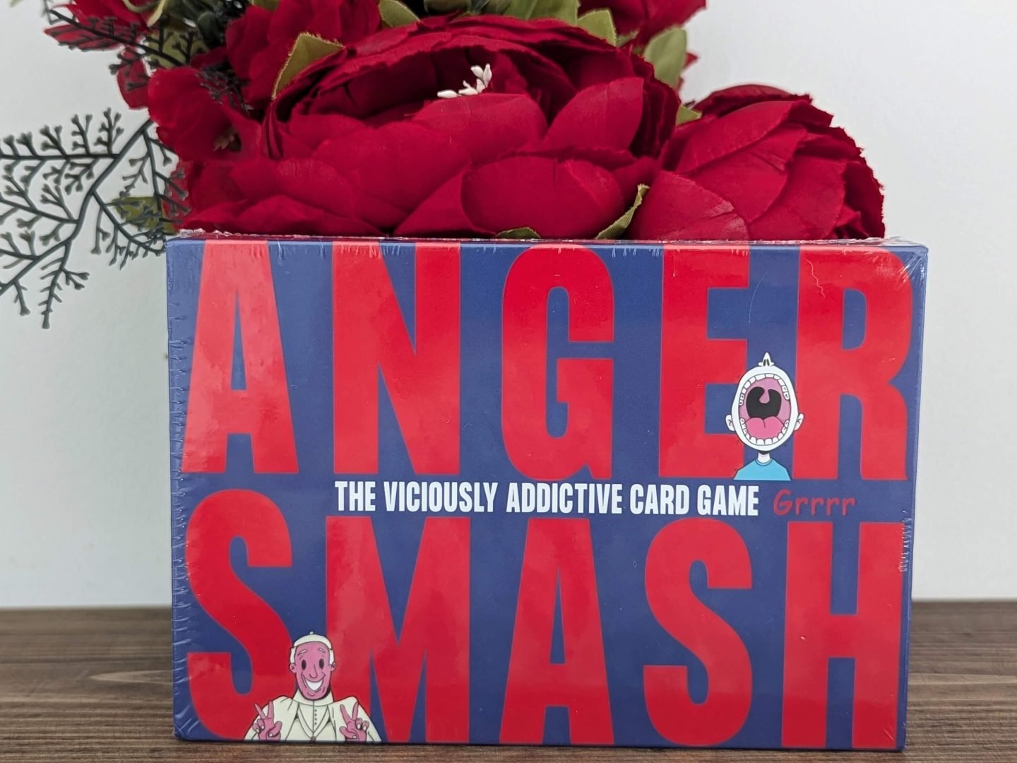 Four gift rule something you want: Anger Smash card game displayed in front of red flowers