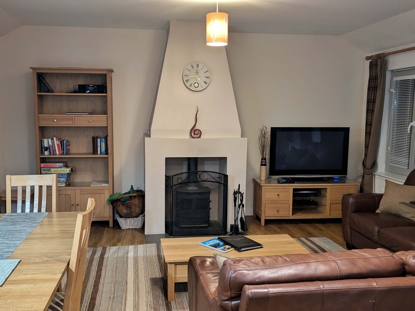 Living room in dog friendly holiday cottage with fireplace, sofa, television and dining table visible