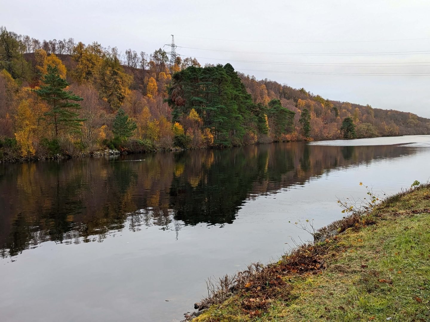 Autumn by the Caledonian canal with orange leaves on trees reflected in the water