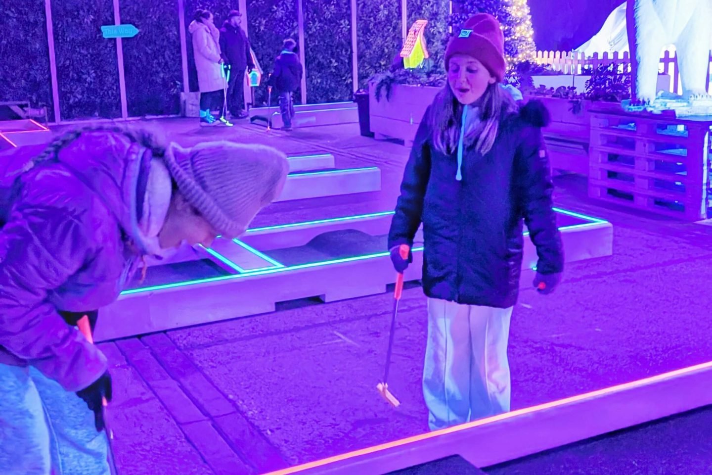 Lia laughing at Libby playing UV crazy golf at Winter Glow Malvern Worcestershire 2025