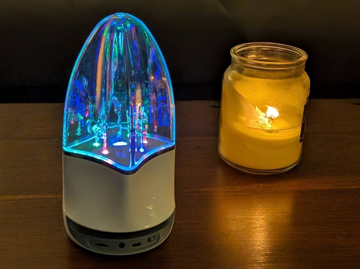 Aqua Bluetooth Speaker on a dark wood table next to a lit white candle