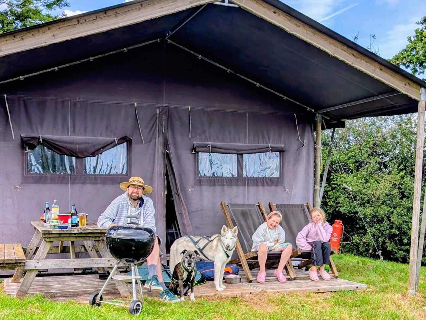A man with two girls and two dogs sitting outside the glamping hideaway at Billingsmoor Farm