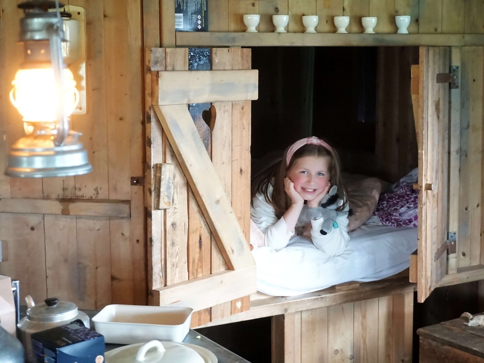 Girl in a cupboard bed at Billingsmoor Farm in a Feather Down glamping canvas hideaway