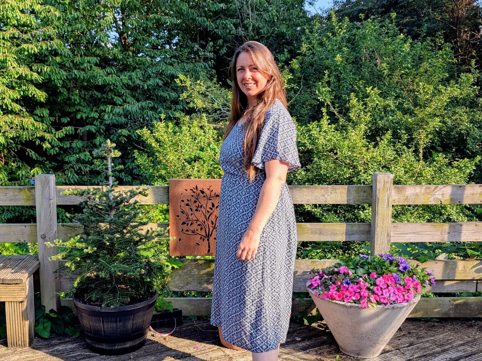 Natalie in a printed maxi dress in front of flowers in the garden