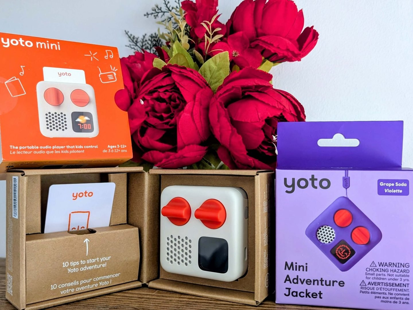 Yoto Mini player and purple case displayed in front of red Christmas flowers