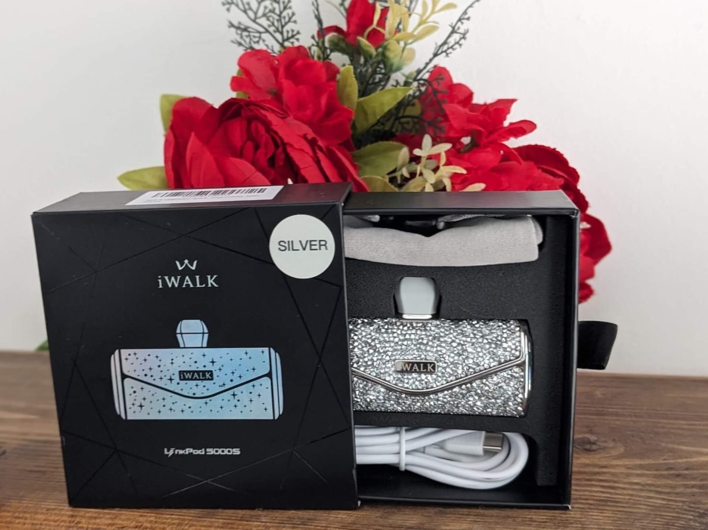 iWalk sparkly phone charger for teens and tweens in box on wooden shelf with red Christmas flowers behind