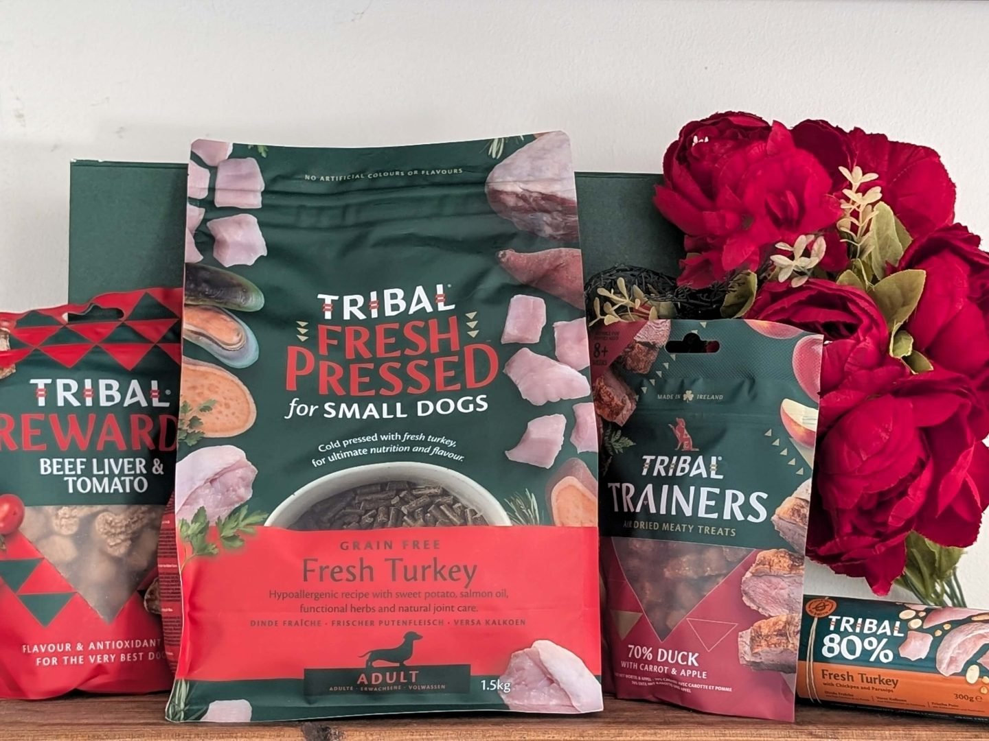 Tribal dog food on a wooden shelf next to red Christmas flowers