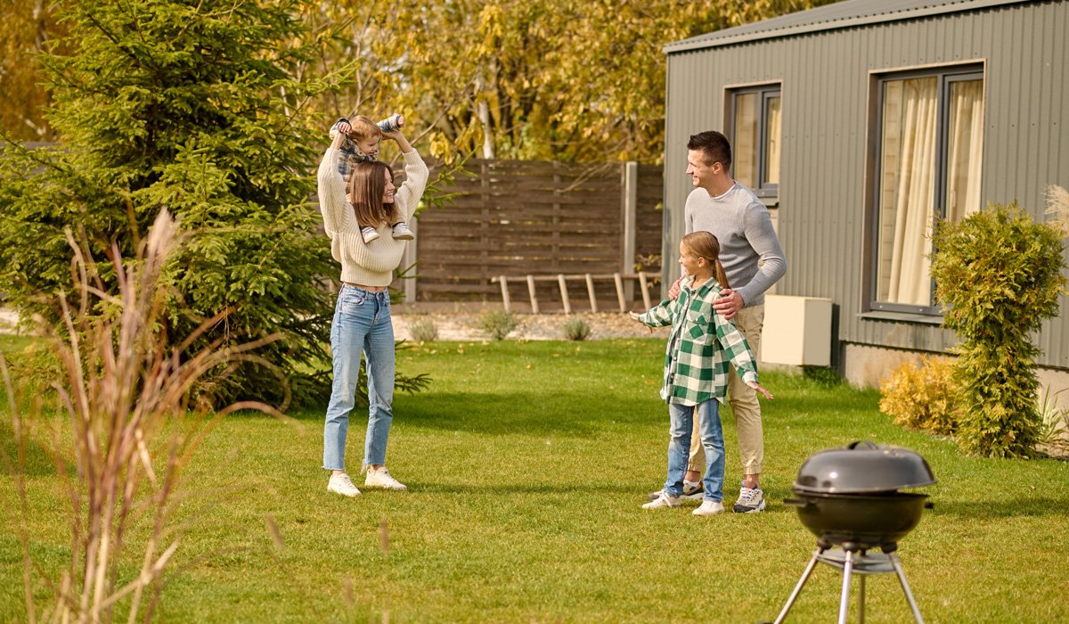 Family playing in backyard near grill