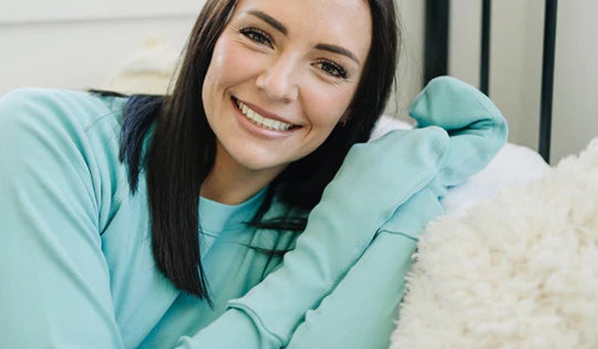 Smiling woman in teal sweatshirt on couch