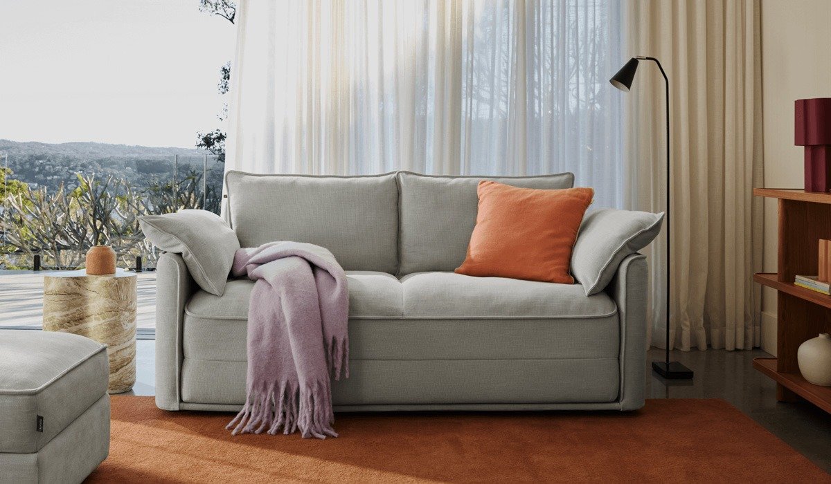Light grey sofa with orange pillow and throw