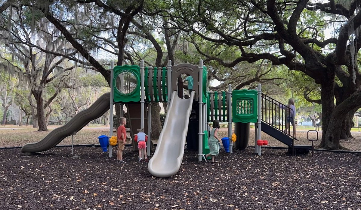 Photo from WillyGoat Children playing on playground slides under oak trees