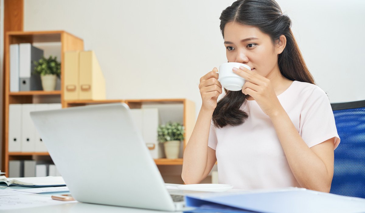 Woman drinking coffee at office desk
