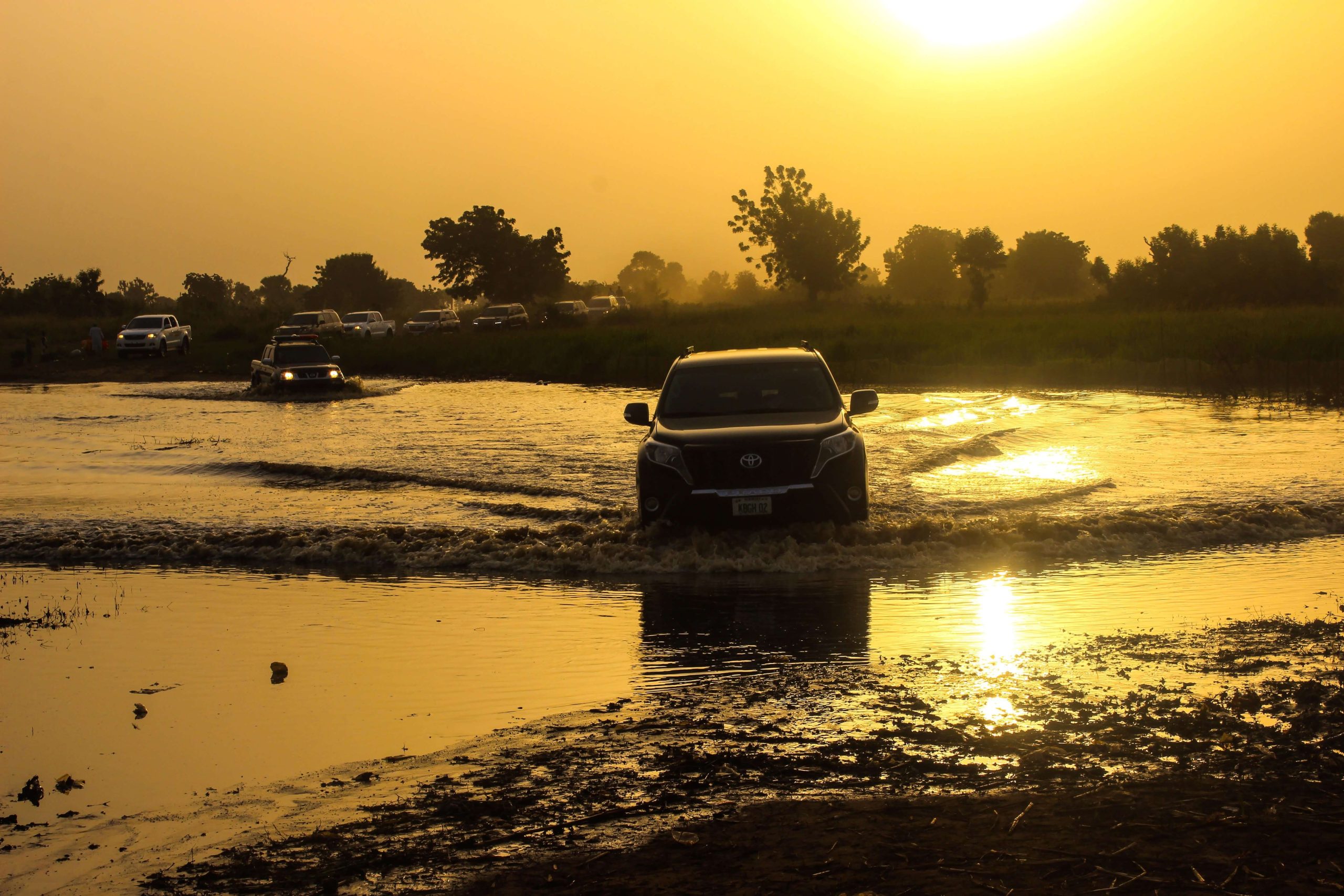 Car driving through water at sunset