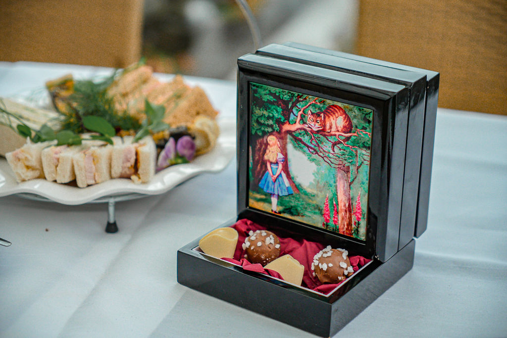 Alice in Wonderland themed afternoon tea at Ralph Court Gardens in Herefordshire, West Midlands handmade chocolates displayed in a box with Alice in Wonderland and the Cheshire Cat on it