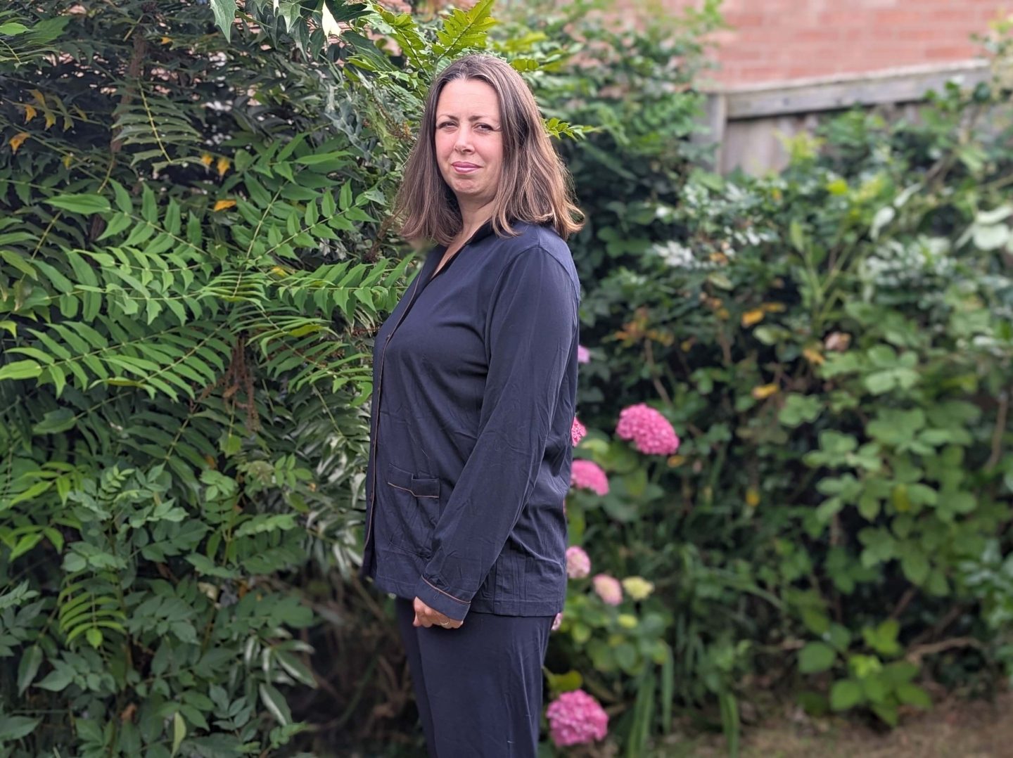 Natalie standing in the garden wearing Dark blue copper-infused pyjamas from Copper clothing