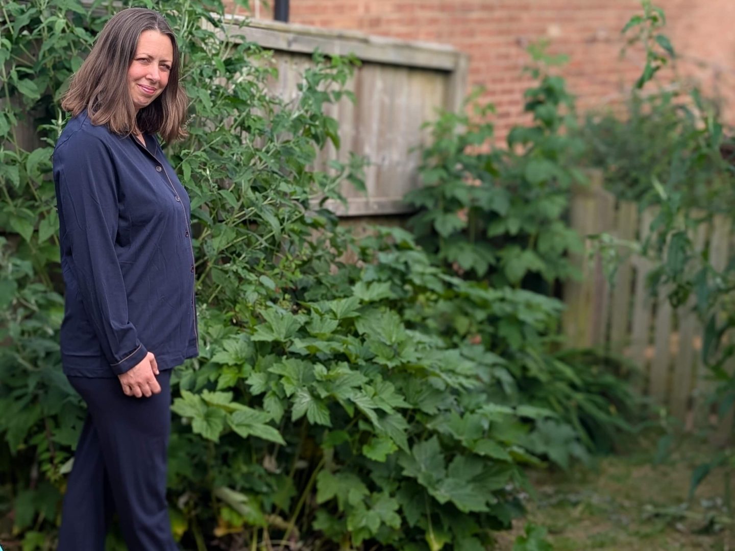 Natalie standing in the garden wearing Dark blue copper-infused pyjamas from Copper clothing