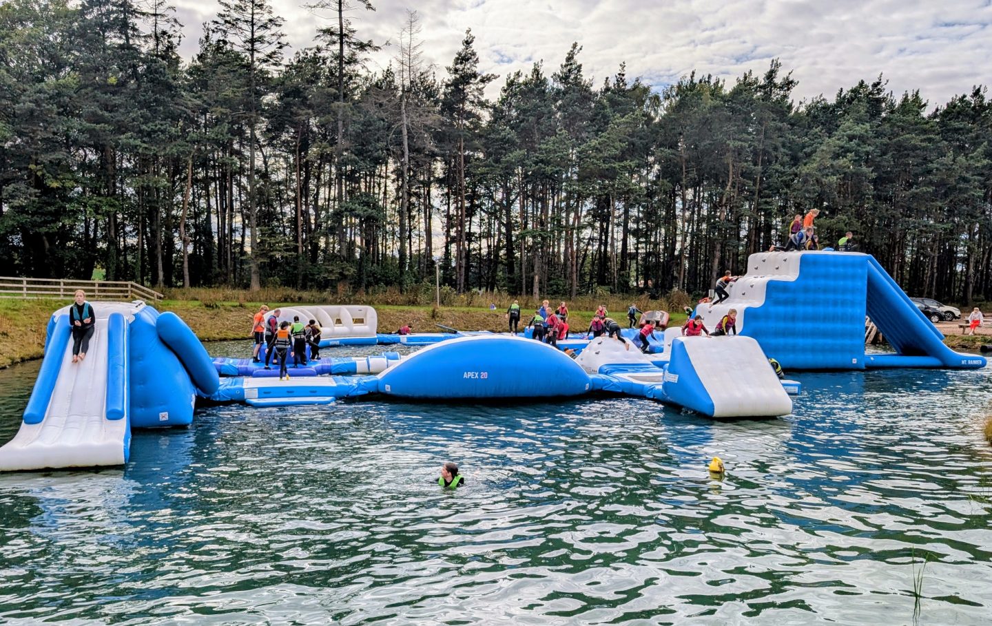 People playing on an inflatable Aqua Park at Foxlake in East Lothian - the area around the outside of the lake is dog friendly